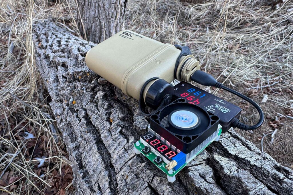 A multimeter and dummy load resistor connected to a power bank during an efficiency and capacity test.