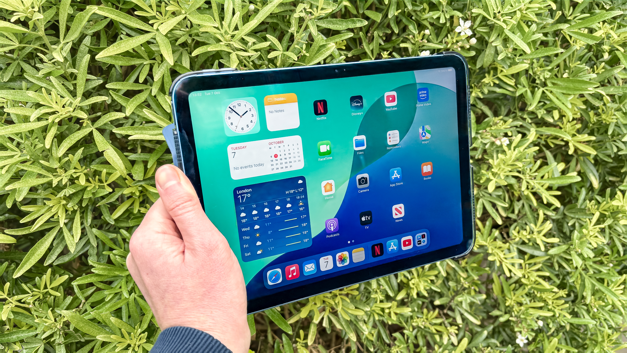 Hand holding the entry-level iPad 11 outdoors.