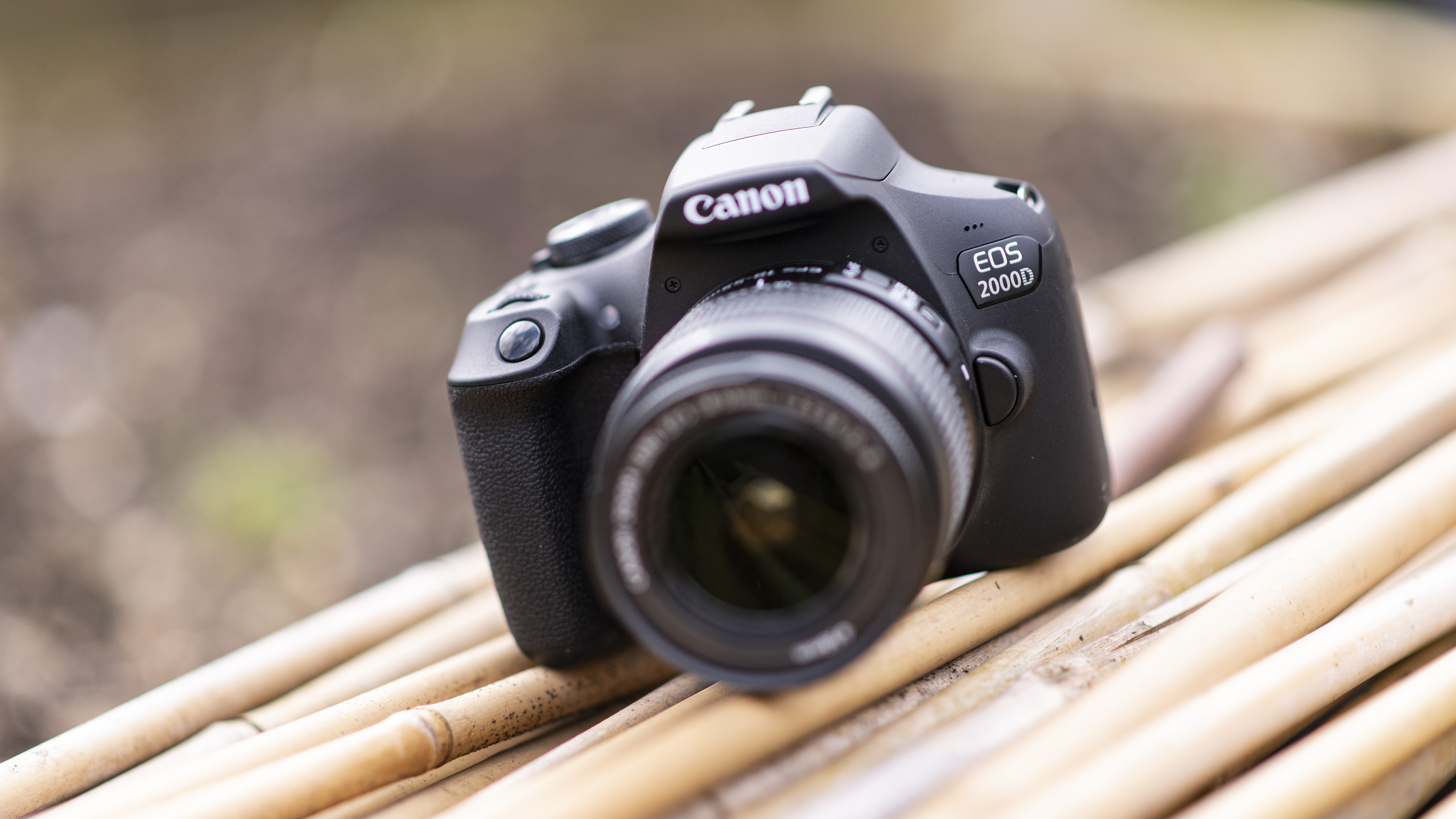 A Canon EOS 2000D DSLR camera resting on a natural background.