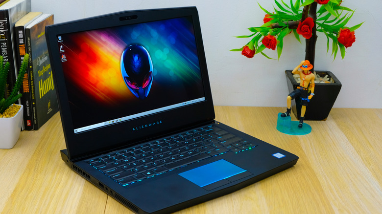 An Alienware gaming laptop with its signature glowing logo and keyboard on a desk.