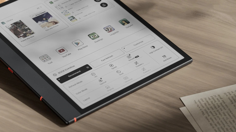 Boox Note Air5 C tablet lying on a desk next to physical notebooks and pens.