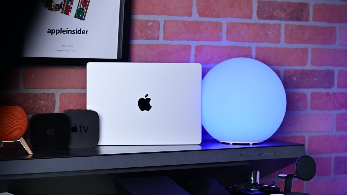 Silver MacBook Pro sitting on a shelf alongside smart home accessories.