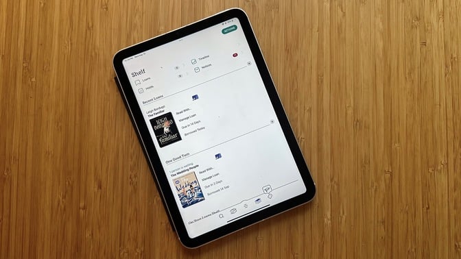 An iPad Mini showing a colorful library application interface.