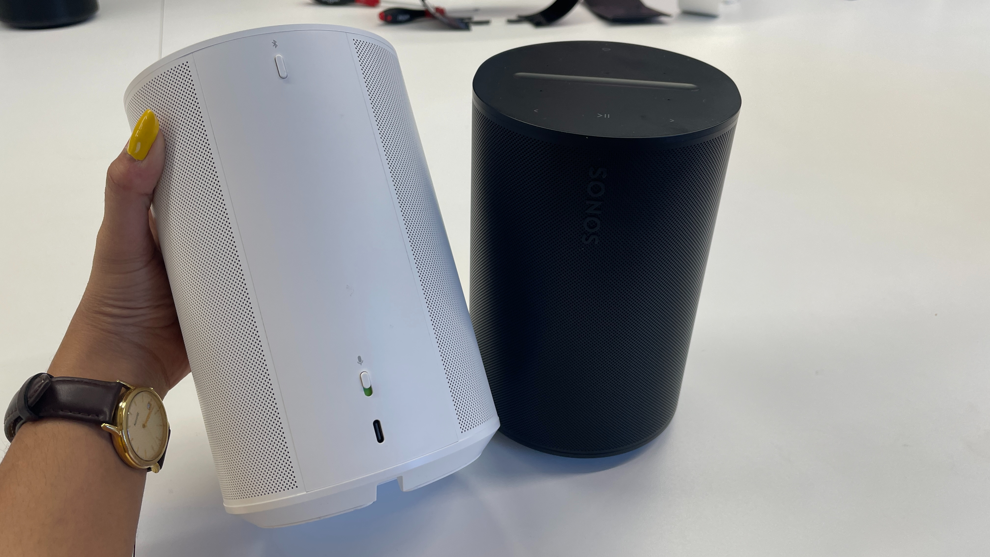 A white Sonos Era 100 and a black Sonos Era 100 being compared side-by-side.