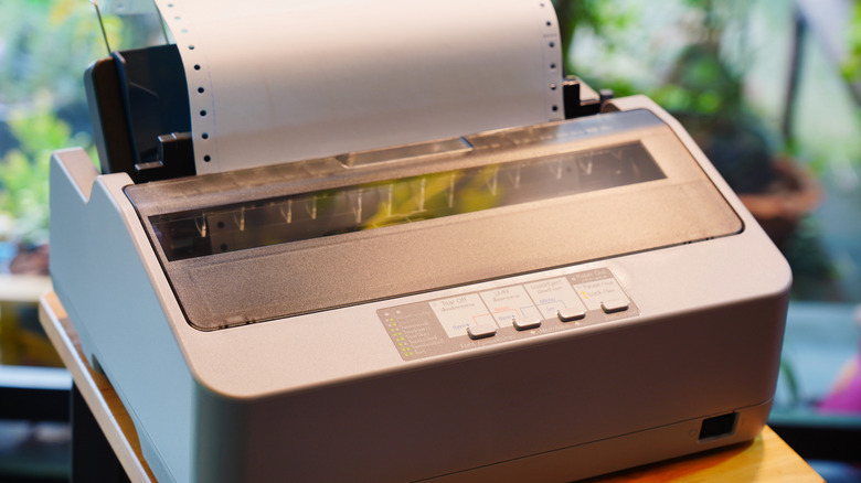 A dot-matrix printer with perforated continuous form paper and green-and-white stripes.