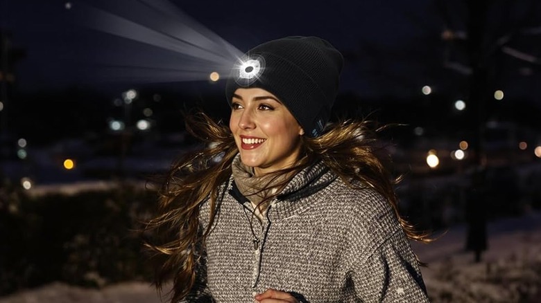 A woman wearing a Bluetooth beanie with the LED light turned on while running at night.