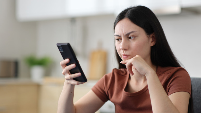 A person looking at a smartphone screen with an expression of annoyance.