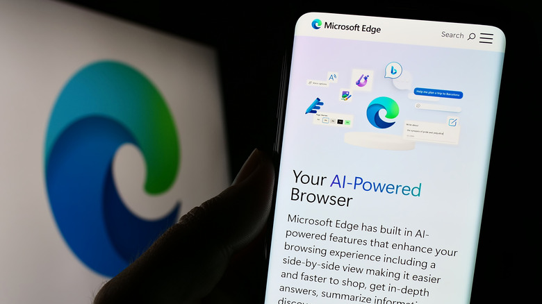A person holding a smartphone with the Microsoft Edge browser logo clearly visible on the screen.