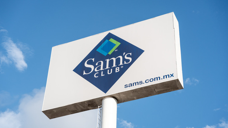The Sam's Club logo on an outdoor warehouse sign against a blue sky.