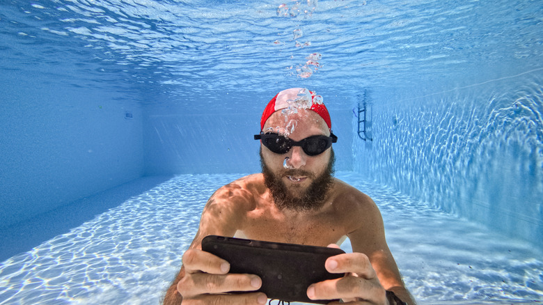 A person holding an iPhone underwater to demonstrate its water resistance and physical durability.