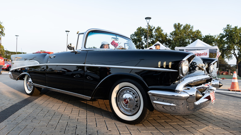 A yellow 1957 Chevrolet Bel Air convertible at a classic car show.