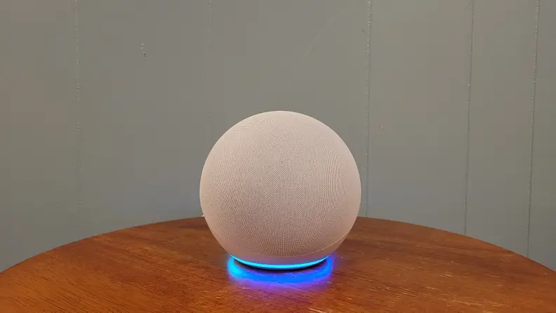 A spherical Amazon Echo 4th Gen speaker with a glowing blue light ring on a wooden table