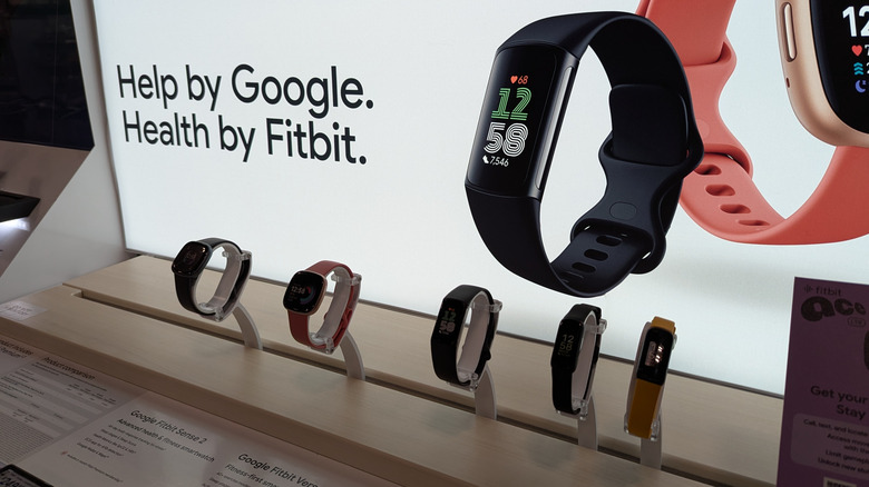 A retail display showcasing various Fitbit smartwatches and fitness trackers.
