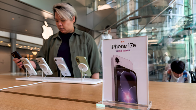 A person looking at various smartphone models in a bright retail store.