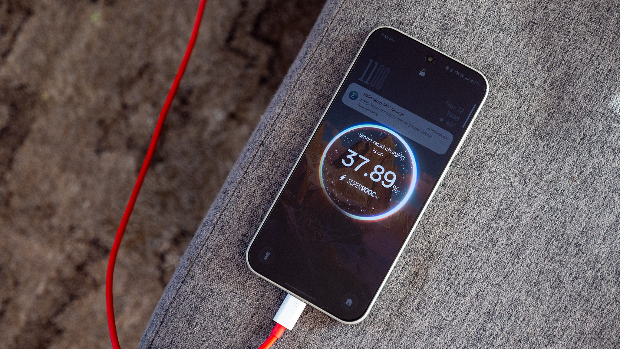 The OnePlus 15 being charged with a red SuperVOOC cable and power adapter.