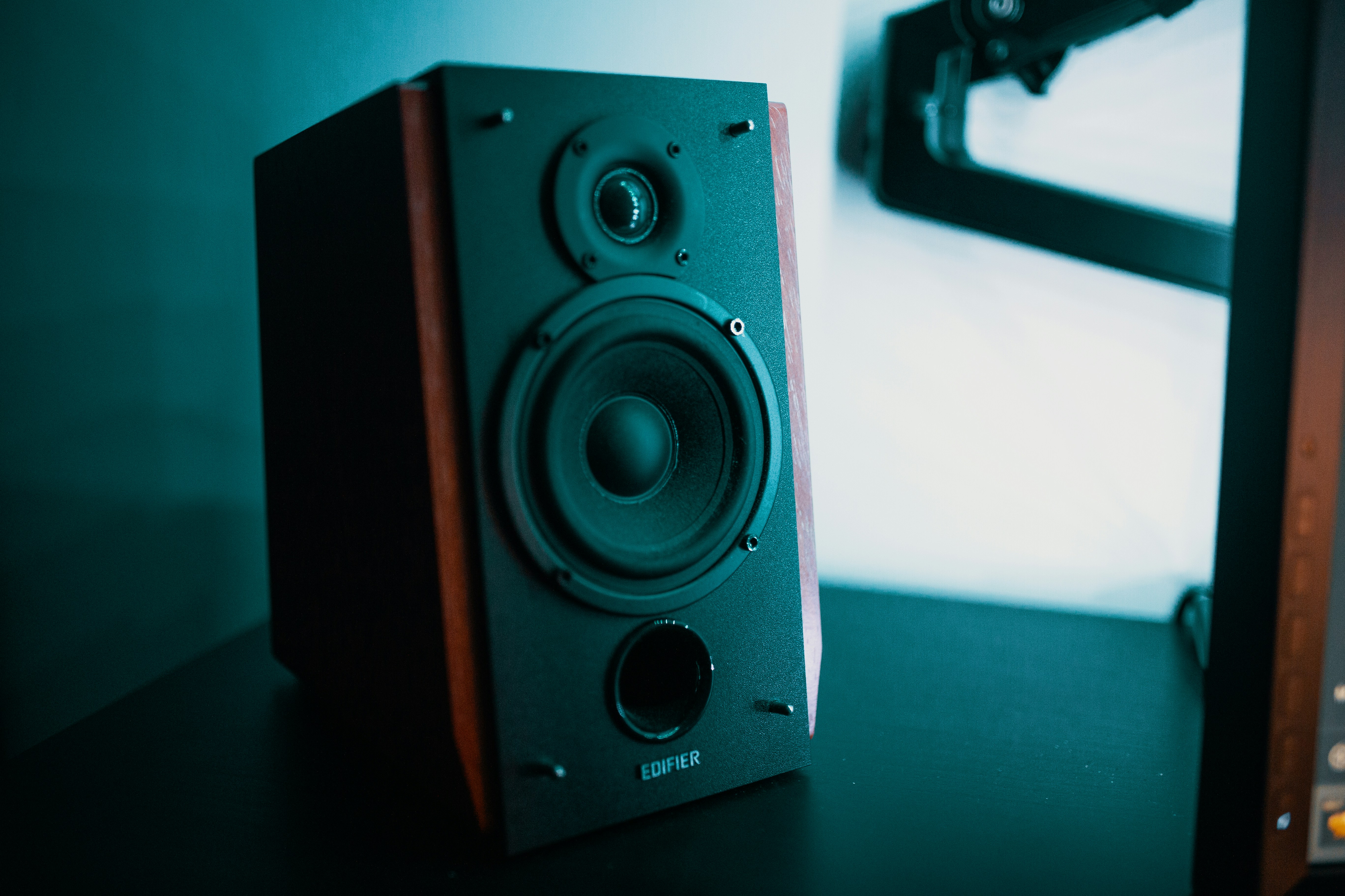 A center channel speaker positioned directly underneath a flat-screen TV at ear level.
