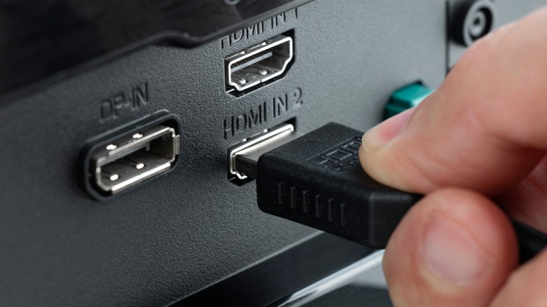 Close-up of a hand connecting an HDMI cable to a female port on a phone adapter.
