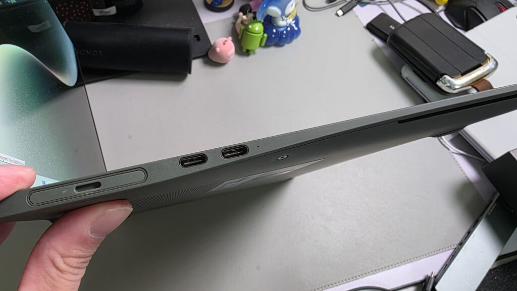 A hand holding the small magnetic detachable camera module above the laptop screen.
