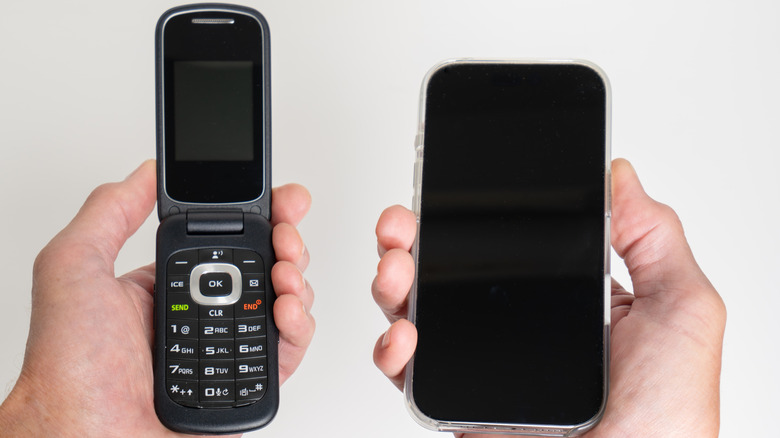 A side-by-side comparison of a person holding a modern touchscreen smartphone and a classic tactile flip phone.
