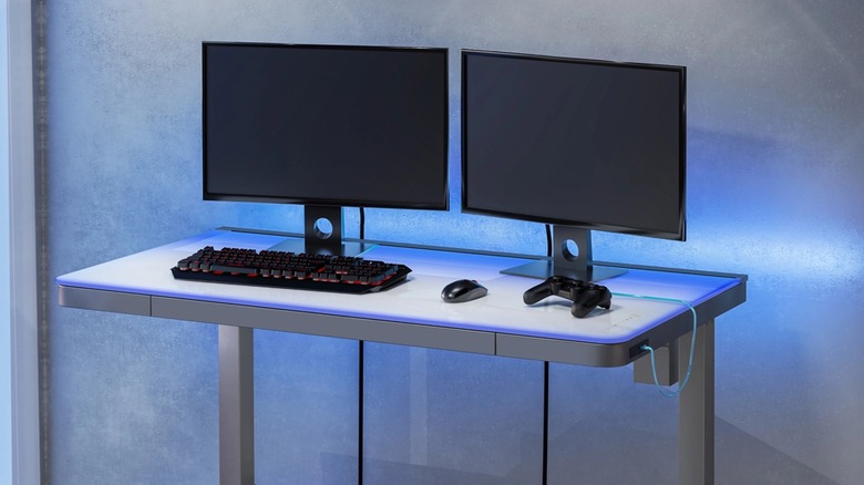A Tresanti motorized adjustable desk in a home office setup with dual monitors.