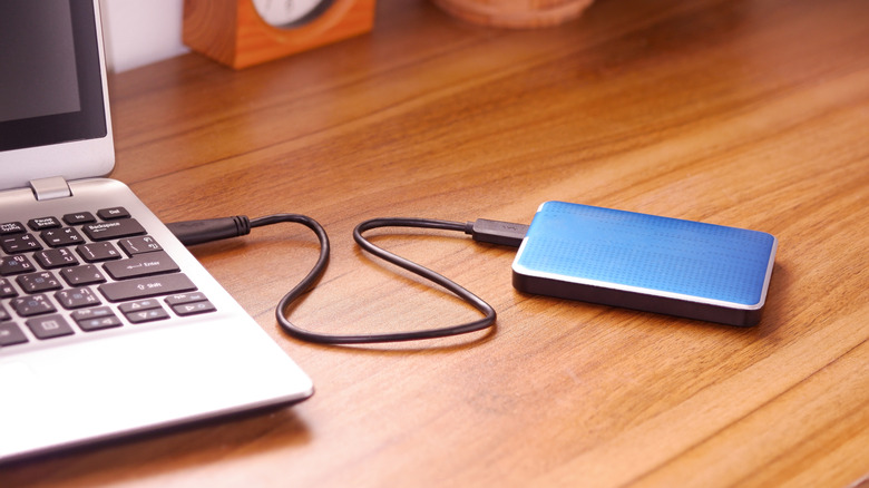 An external SSD drive connected to a laptop, representing high-bandwidth storage.