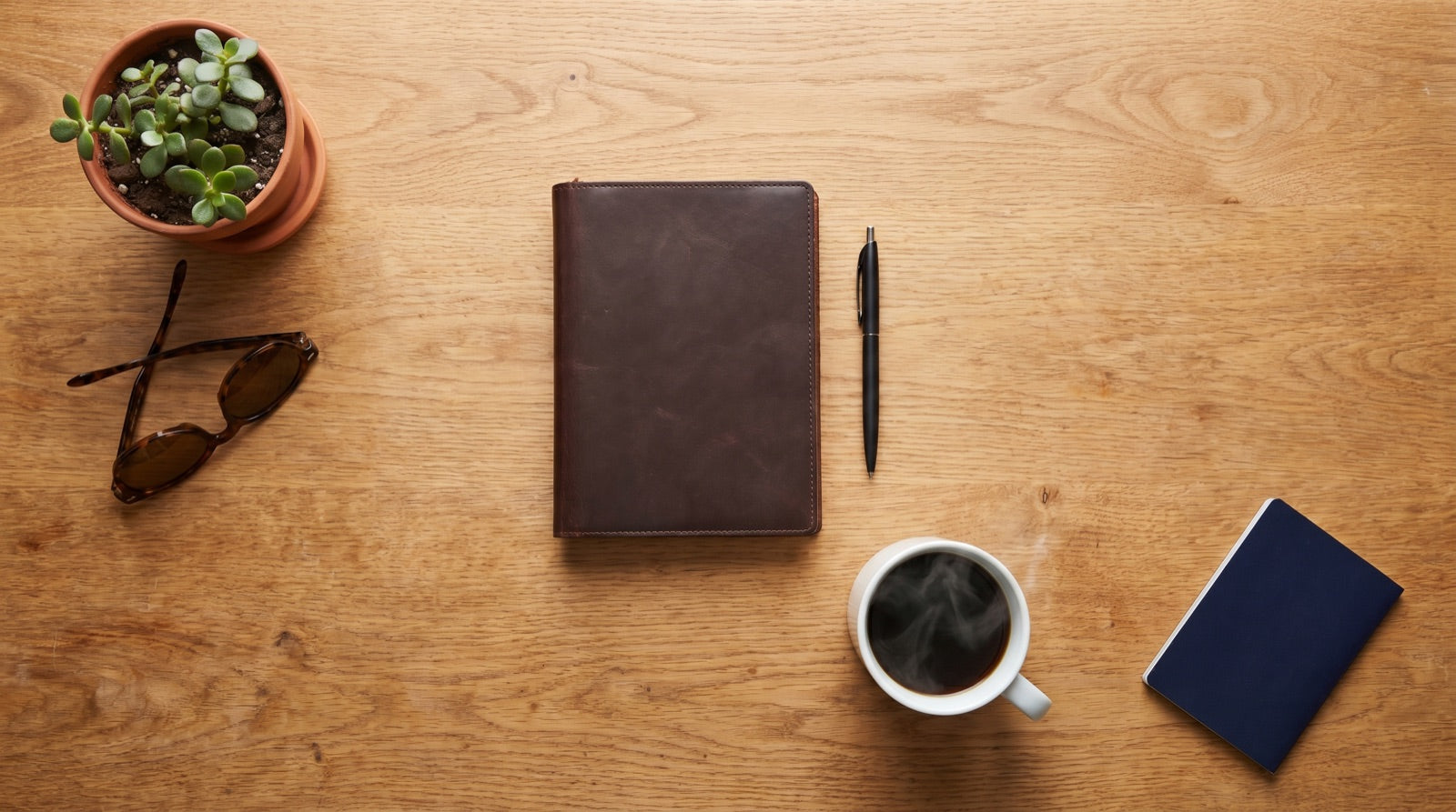 Minimalist flat lay of tech gear and travel essentials on a wooden desk.
