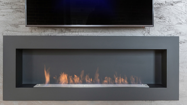 A large flat-screen television mounted on the wall directly above a modern electric fireplace.