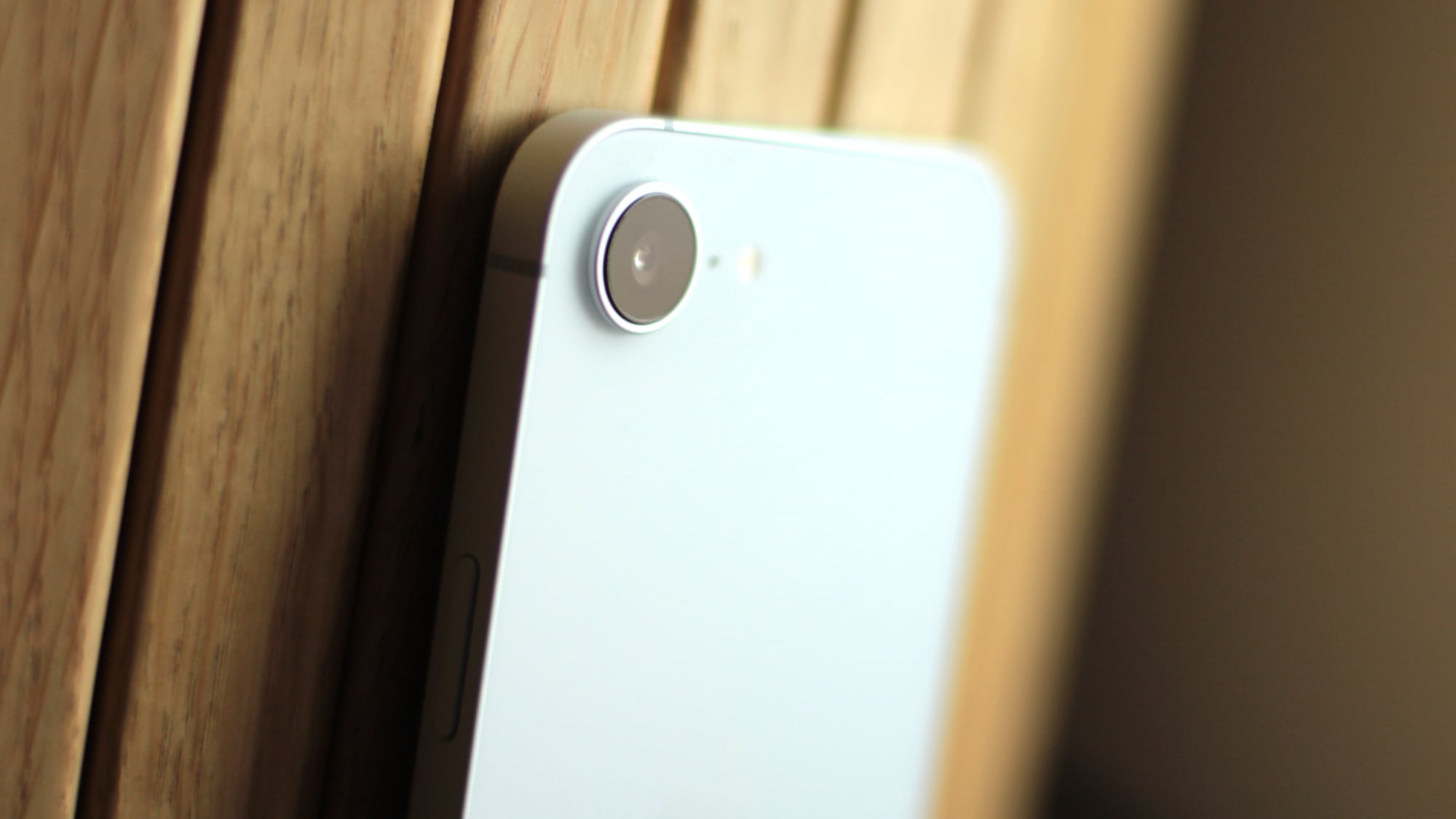 A person holding the iPhone 16e with one hand, demonstrating its compact size.