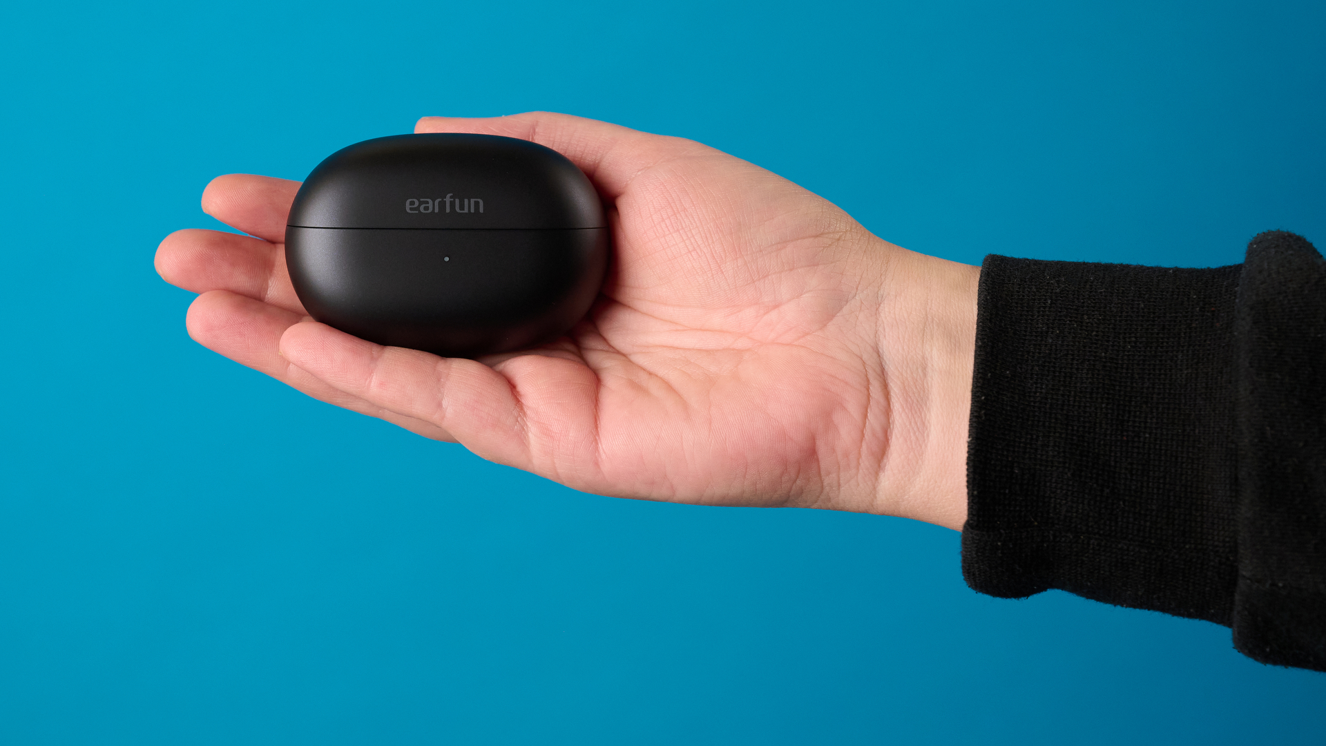 Hand holding an EarFun Clip 2 bud to show the physical control button placement