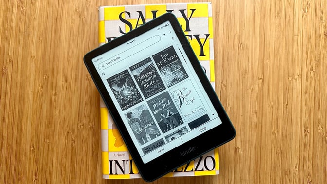 The newest Amazon Kindle Paperwhite resting on top of a hardcover book.