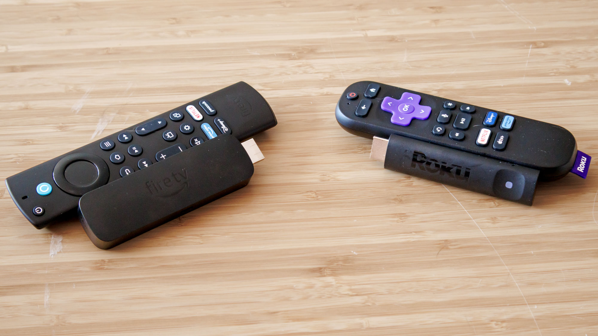 Roku and Amazon 4K streaming sticks displayed together on a surface.