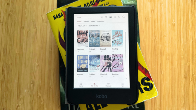 A compact Kobo Clara Colour e-reader resting on a stack of books.