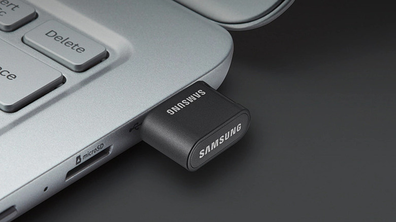 A black Samsung USB 3.0 flash drive plugged into the side of a modern laptop.