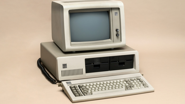 Vintage IBM Personal Computer with two floppy disk drives and a matching monitor.