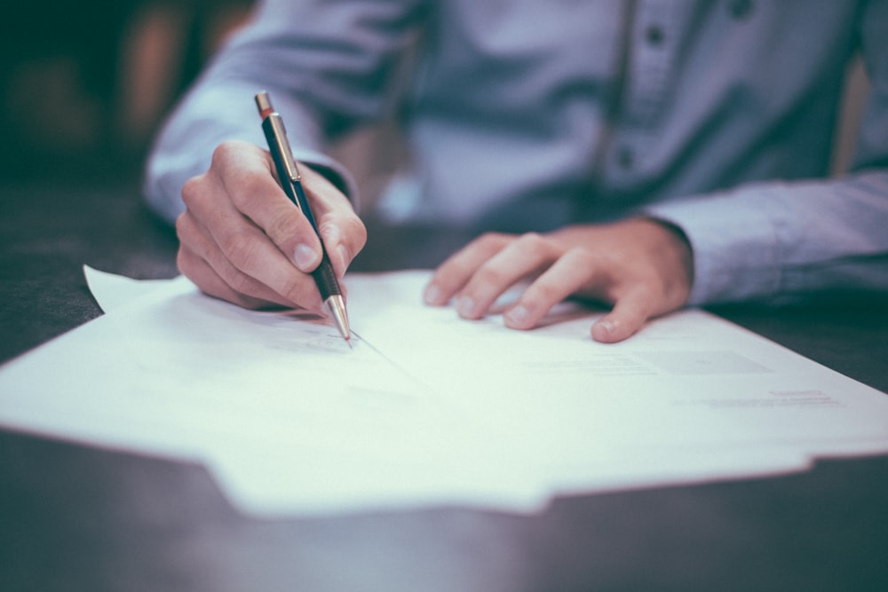 Life insurance policy forms and a pen on a wooden desk.