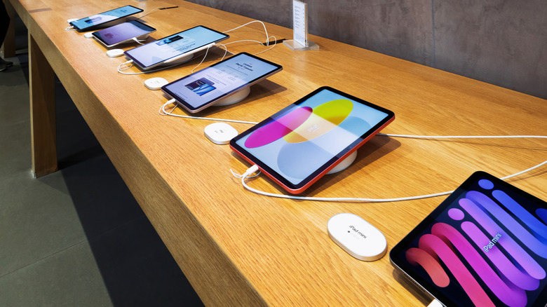 A lineup of various iPad models displayed on a table in an Apple Store.