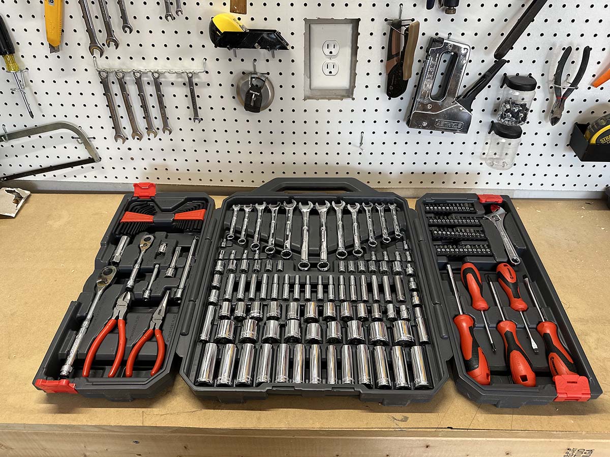 A wide variety of open tool kit cases displayed together on a floor.