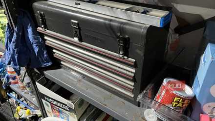 A clean and organized garage workshop with a tool box and workbench.