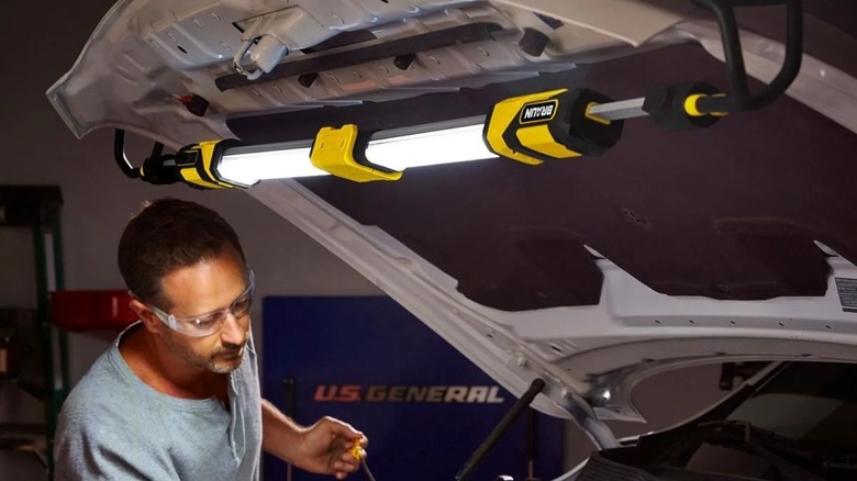 The Braun 2000 Lumen underhood light illuminating a car engine in a dark garage.