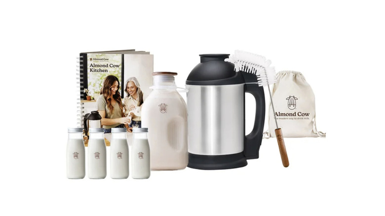 An Almond Cow plant-based milk maker with its accessories and instruction manual on a counter.
