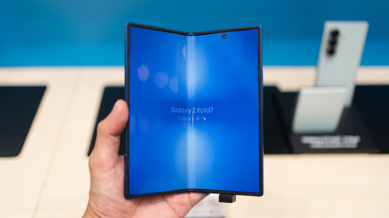 A person holding a Galaxy Z Fold 7 inside a brightly lit Samsung retail store.