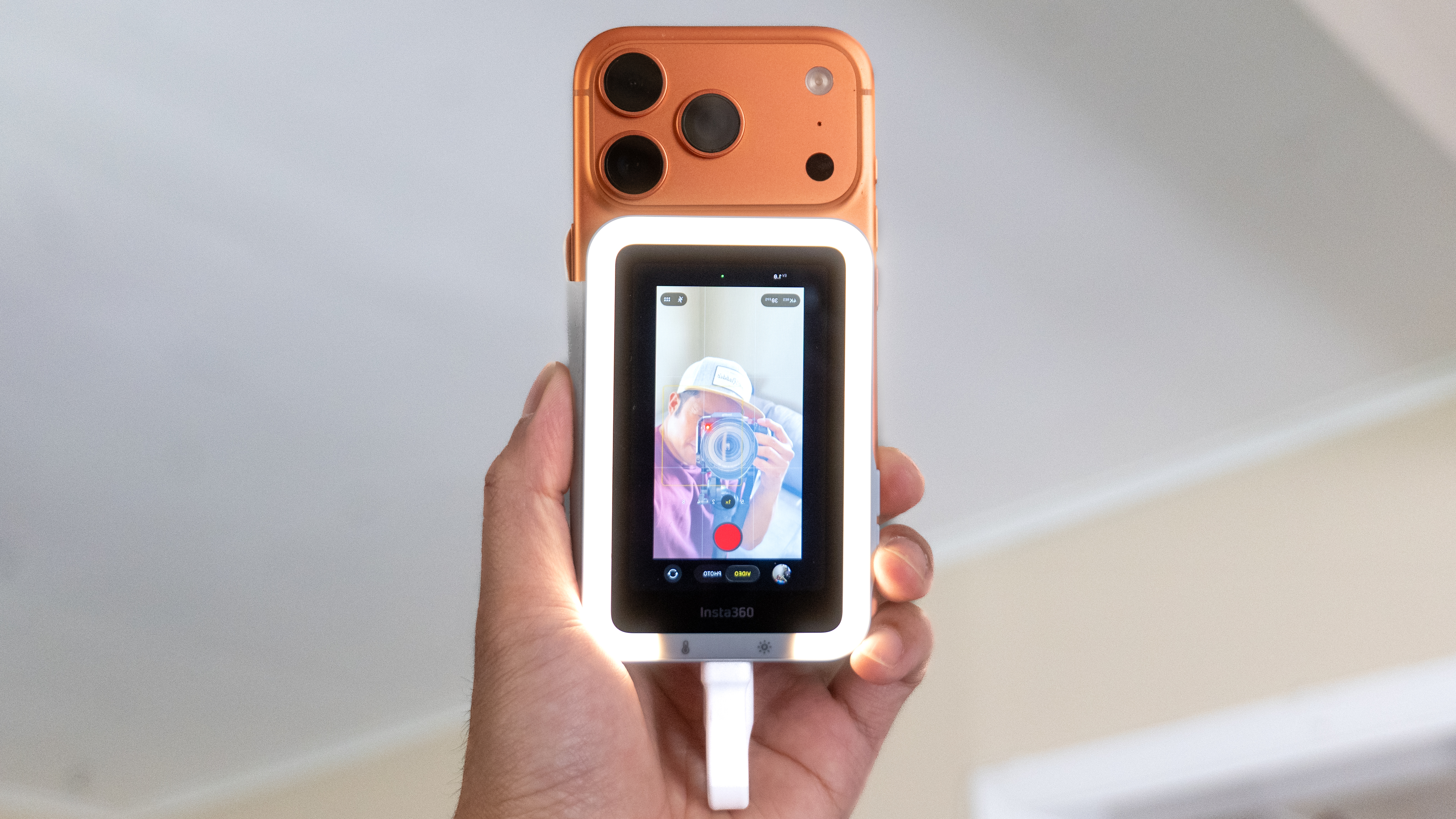 A content creator holding an iPhone with the Insta360 Snap screen to frame a selfie vlog.