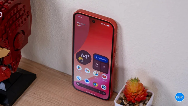 The sleek Google Pixel 10a mid-range smartphone leaning against a textured wall.