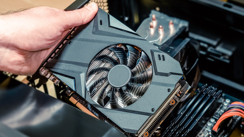 A hand installing a graphics card into the PCIe slot of a PC motherboard.