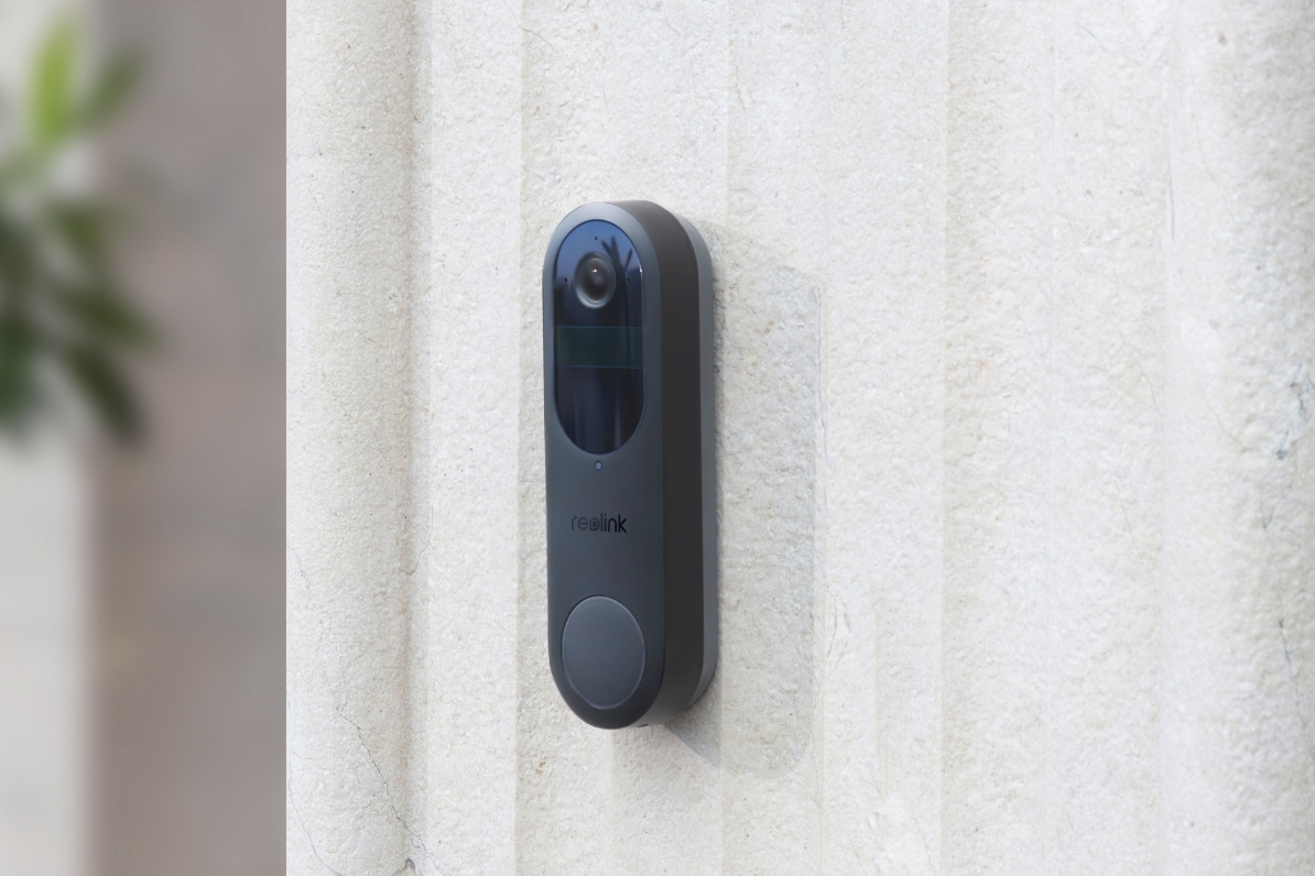 A Reolink Battery Doorbell mounted on a grey textured exterior wall.