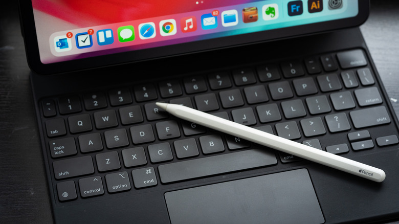 An iPad connected to a Magic Keyboard with an Apple Pencil resting nearby.