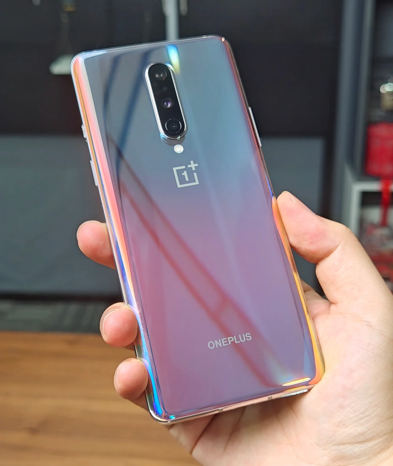 OnePlus smartphone on a desk alongside its signature red cable and large charging brick.