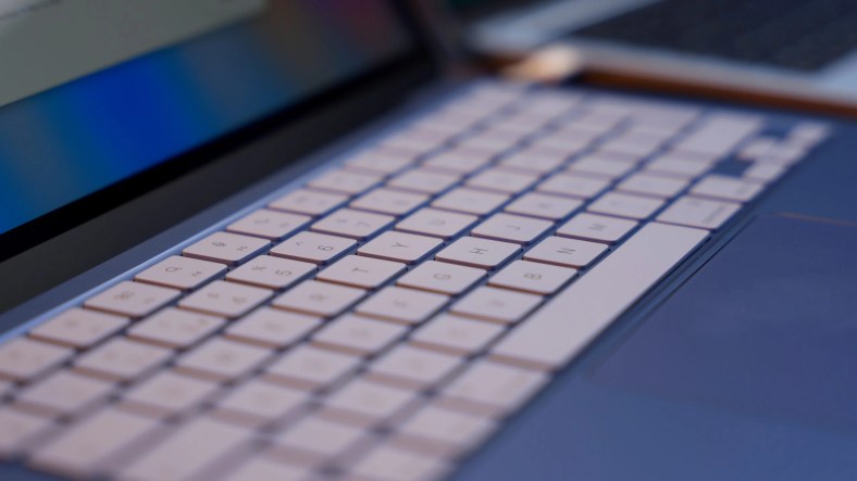 Side profile of a thin silver MacBook Neo laptop on a neutral background.
