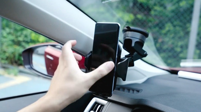 Hand adjusting a smartphone secured in a windshield mount