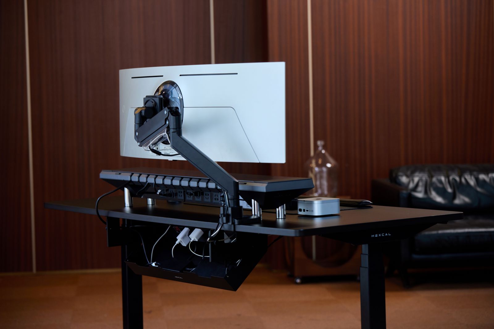 An under-desk metal tray holding a power strip and multiple organized black cables.